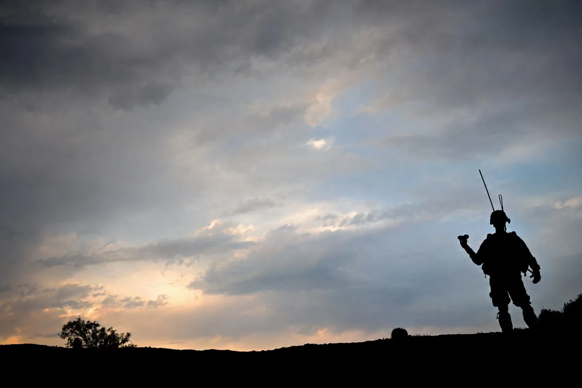 A U.S. military operator launching a tactical drone at dusk on the open prairie